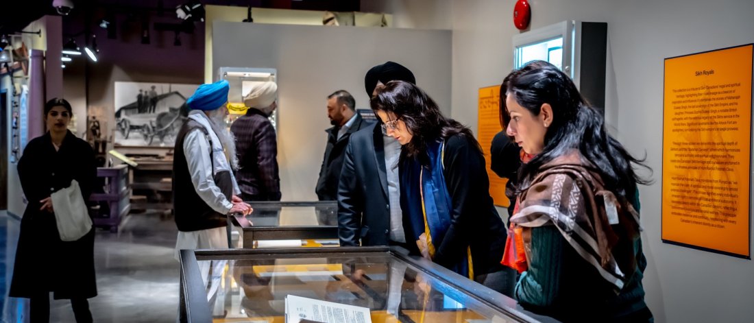  Visitors attentively viewing an exhibition display in a museum gallery.